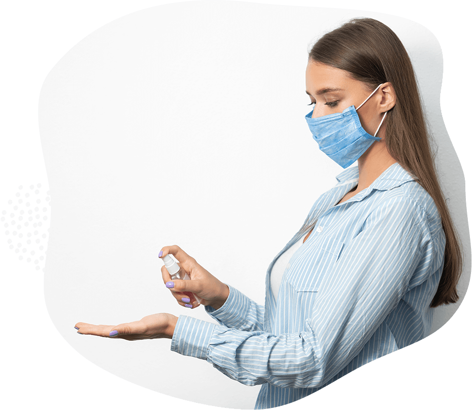 Bild einer Frau mit Mundschutz, die sich Desinfektionsmittel in die offene Hand sprüht